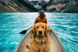 woman canoeing in mountains with dog looking angrily into camera