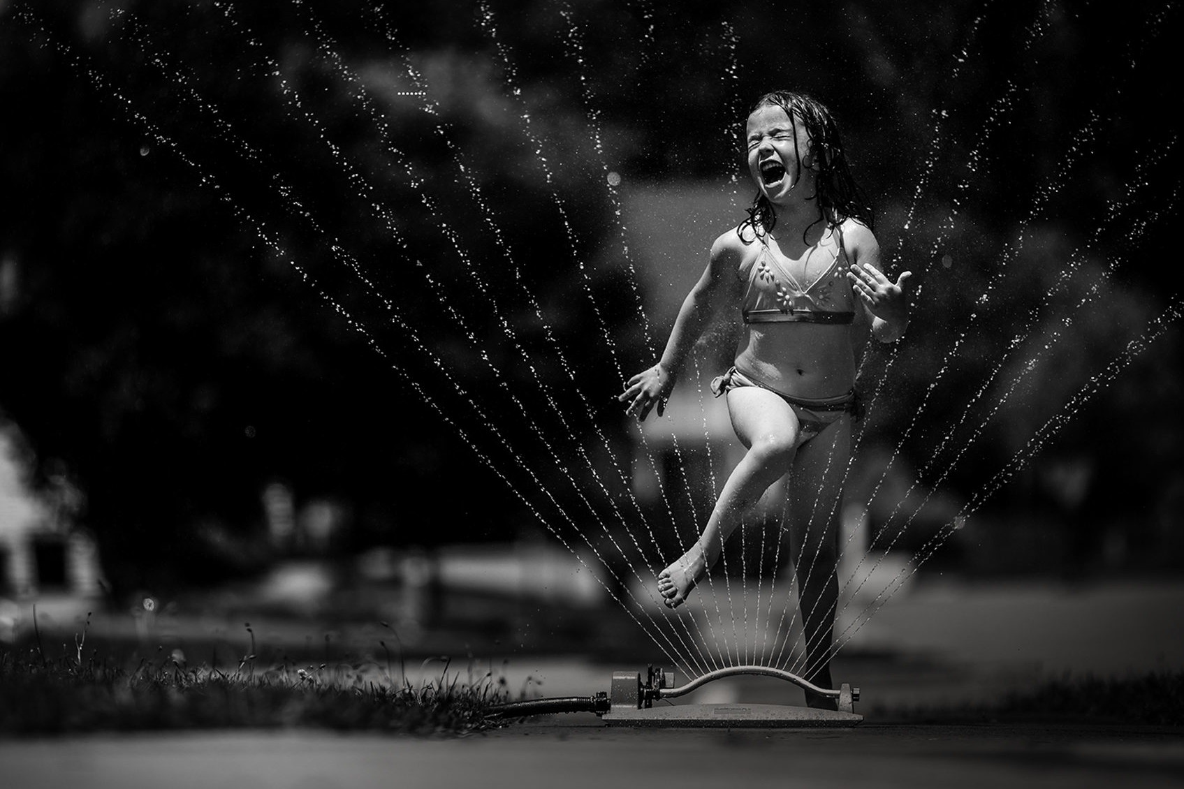 evolve young girl playing in sprinkler