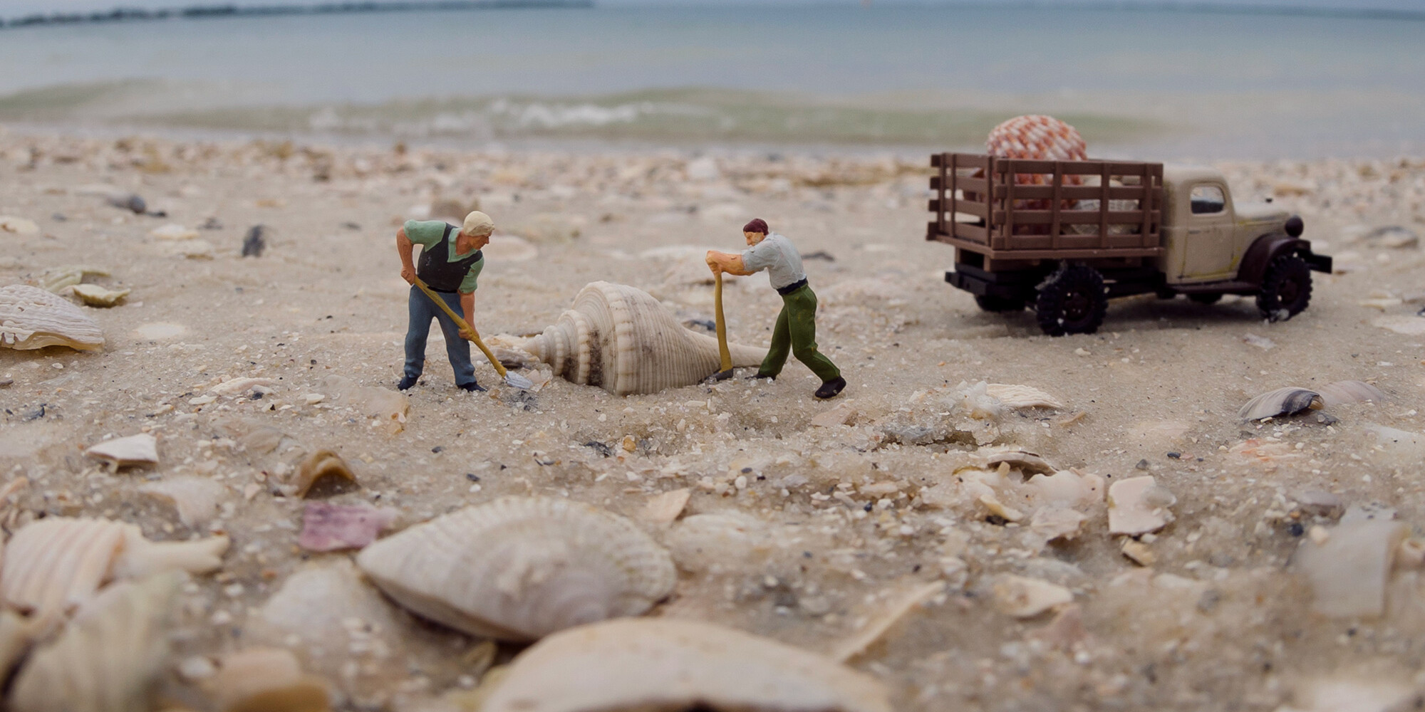 mini figures of men digging up a shell on the beach to put in a mini truck