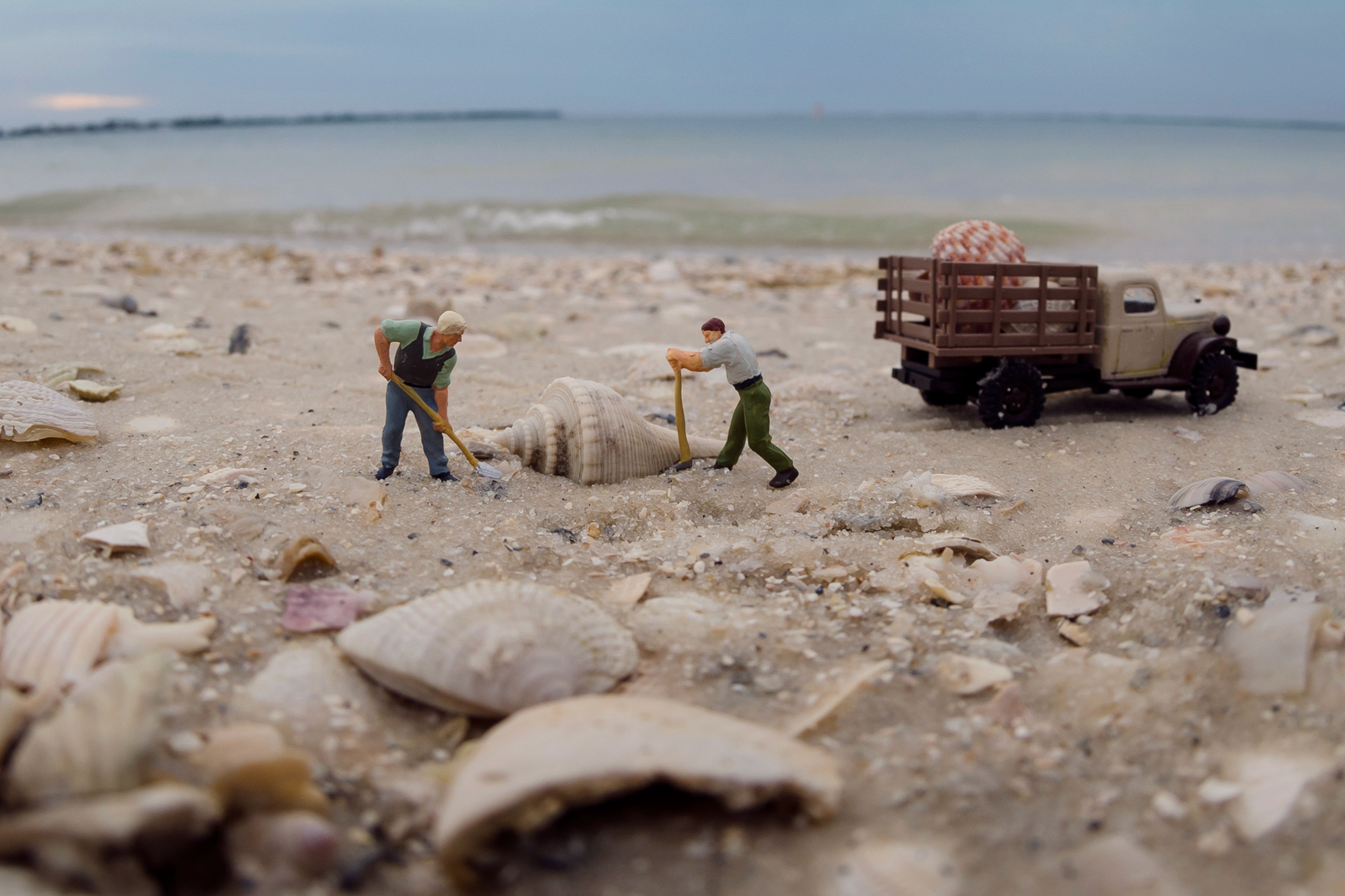 mini figures of men digging up a shell on the beach to put in a mini truck